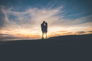 Picture of a couple silhouetted against a beautiful sunset.