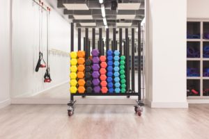 A rack of multi-colored dumbell exercise weights.