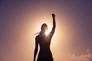 Strong confident woman celebrating a victory with her fist in the air. 