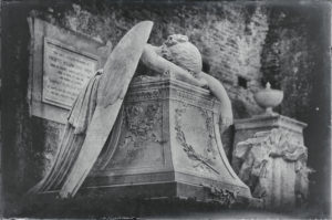Angel face down on a dais.  Wings and arms draped over the platform.  Black and white image.